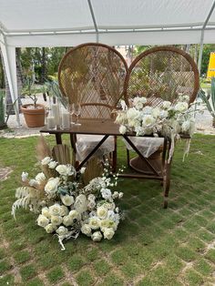 an outdoor table with chairs and flowers on the grass in front of a white tent