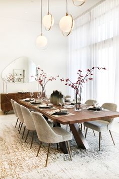 a dining room table with chairs, plates and vases on it in front of a large window