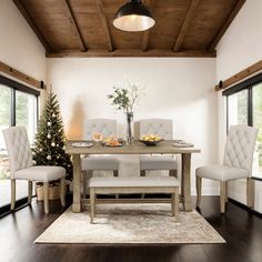 a dining room table with white chairs and a christmas tree