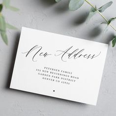 a close up of a card with the word new address on it next to a plant