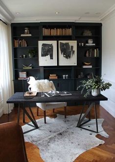 an office with black bookcases and white cow hide rug on the floor in front of it