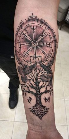 a man's arm with a compass and tree tattoo on the side of his leg