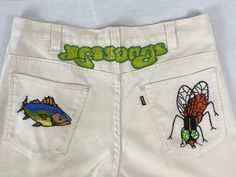 "Vintage 1970s Levi's Sta Prest pants. Made of cotton/poly white denim. Has Rock and Roll band, fly and fish embroidered on back. Intricate embroidery! \"YES SONGS\" Has Levis big E label, Talon zip fly, two waist pockets, and two rear pockets. Label reads: Levis sta-prest never needs ironing. Style 546. Actual measurements are:  32\" at the waist  33\" inseam  43\" hips  24\" thighs  11\" rise  Overall length 44\"  20\" foot opening In good condition. Some faint yellow areas throughout." Retro White Bottoms For Streetwear, Retro White Jeans For Spring, Vintage White Bottoms For Spring, Vintage White Pants For Spring, White Vintage Pants For Spring, White Retro Pants For Streetwear, White Retro Jeans For Spring, Vintage Style White Bottoms For Streetwear, Retro White Bottoms With Pockets