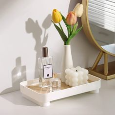 a white tray with flowers and perfume bottles on it