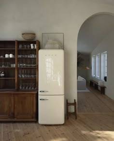 a white refrigerator freezer sitting in a kitchen next to a book shelf filled with glasses