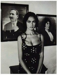 black and white photograph of a woman sitting in front of two portraits