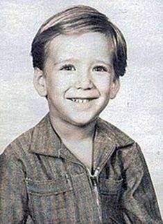 an old photo of a young boy with a smile on his face and wearing a striped shirt