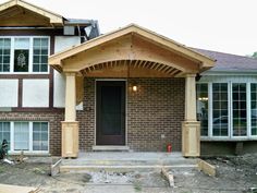 a house that is being built with brick and wood trimming on the front porch