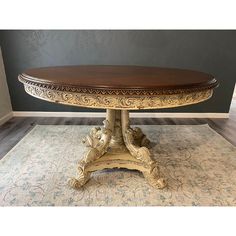 a large wooden table with ornate carvings on the top and base, sitting on a rug