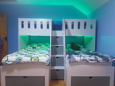 two bunk beds with drawers underneath them in a room that has blue walls and wooden floors