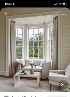 a living room filled with white furniture and large windows overlooking a lush green park area