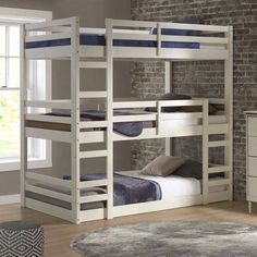 a white bunk bed sitting next to a brick wall in a room with hardwood floors