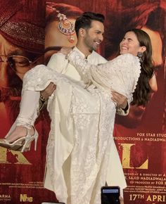 a man holding a woman in front of a movie poster