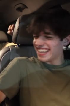 a young man sitting in the back seat of a car