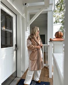 a woman is standing on the front porch