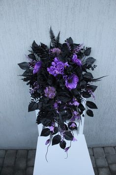 a bouquet of purple flowers sitting on top of a white table next to a wall