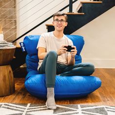 a man sitting on a blue bean bag chair holding a cell phone in his hand