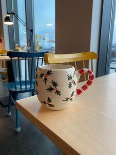 a coffee cup sitting on top of a wooden table next to a blue and yellow chair