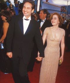 a man in a tuxedo holding the hand of a woman