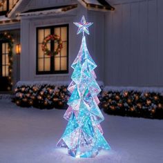 a lighted christmas tree in front of a house