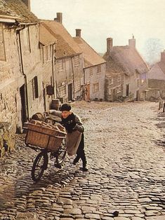 a person riding a bike down a cobblestone street with houses in the background