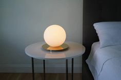 a white lamp sitting on top of a table next to a bed