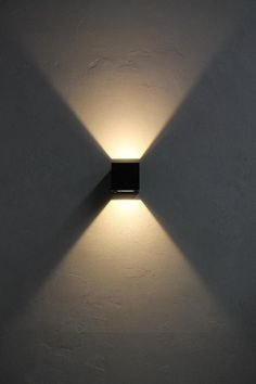 a light that is on the side of a wall with it's shadow cast