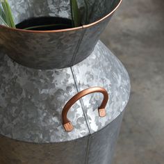 a metal vase with a plant in it