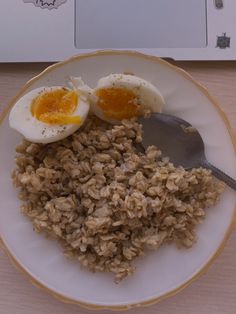 an egg and rice dish on a plate next to a computer keyboard with a laptop in the background