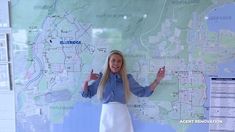 a woman standing in front of a map with her hands up to the camera and smiling