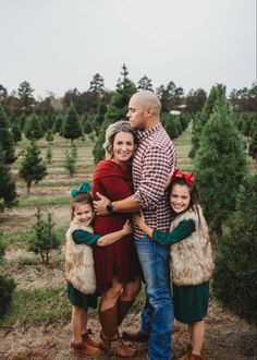 a man and two girls are standing in front of a christmas tree farm with their arms around each other