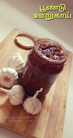 there is a jar of jam on the cutting board with garlics and an onion