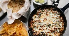 a skillet filled with cheese and tortilla chips next to other food items