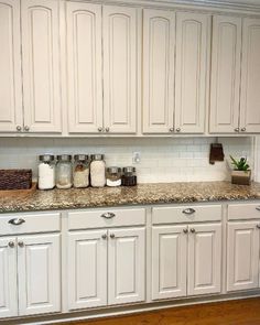 a kitchen with white cabinets and granite counter tops