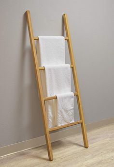 a wooden ladder leaning against the wall with white towels on it's sides and folded in front