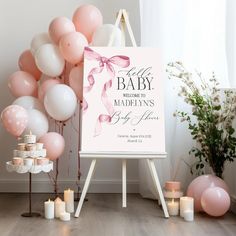 a sign with balloons and candles in front of it that says welcome to the baby