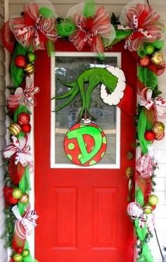 a red door decorated with christmas decorations and an elf's head on top of the door