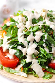 a salad with dressing and tomatoes on a wooden plate