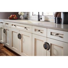 a kitchen with white cabinets and wood flooring next to an open window, on top of a wooden countertop