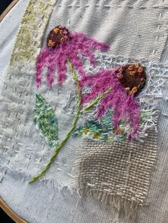 a close up of a embroidery on a piece of cloth with flowers in the middle