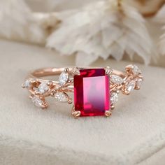 a close up of a ring with a red stone in the middle and white diamonds around it