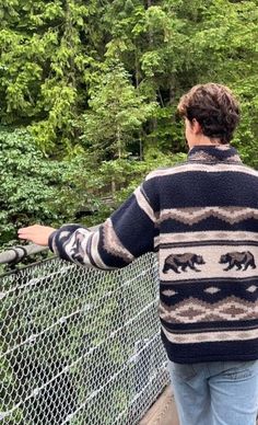 a man is standing on a bridge looking at the bears in the trees behind him