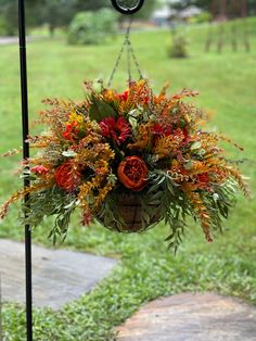 a hanging basket filled with lots of flowers on top of a grass covered park bench