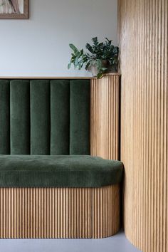 a green couch sitting next to a wooden wall