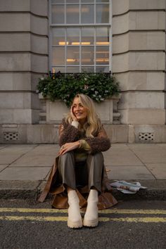 a woman is sitting on the curb talking on her cell phone