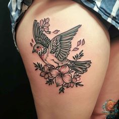 a woman's thigh with a bird and flowers tattoo on the side of her thighs