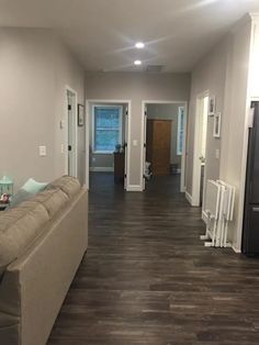 a living room filled with furniture and hard wood flooring on top of a hard wood floor