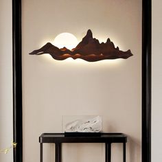 a table with a lamp on top of it in front of a wall mounted mountain