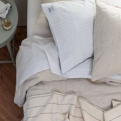 a bed with two pillows on top of it next to a night stand and side table