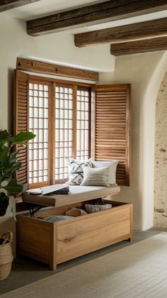 a bed sitting in the middle of a bedroom next to two windows with wooden shutters